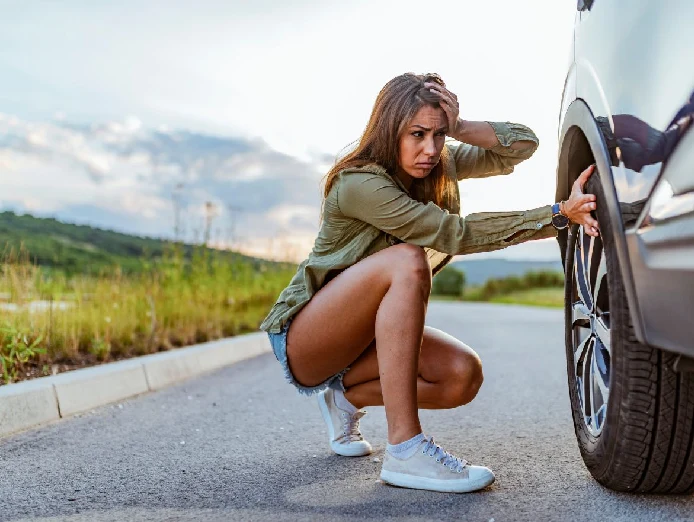 woman checking her tires after hitting the curb