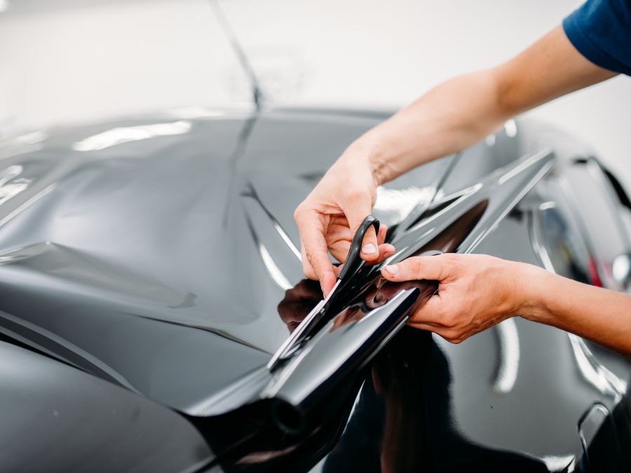A professional cutting black vinyl during a professional car wrap